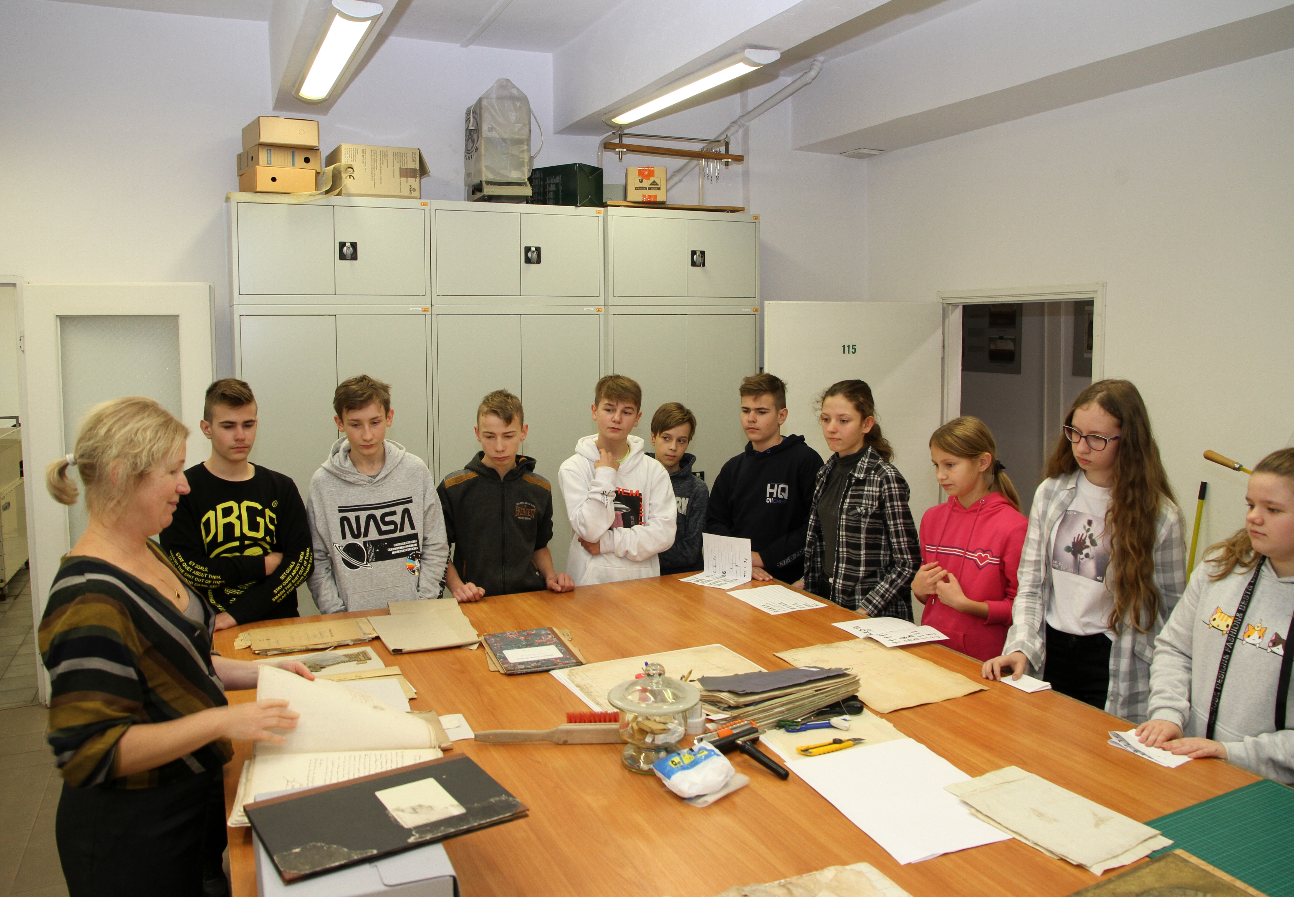 Archiwistka prezentuje grupie uczniów dokumenty archiwalne.