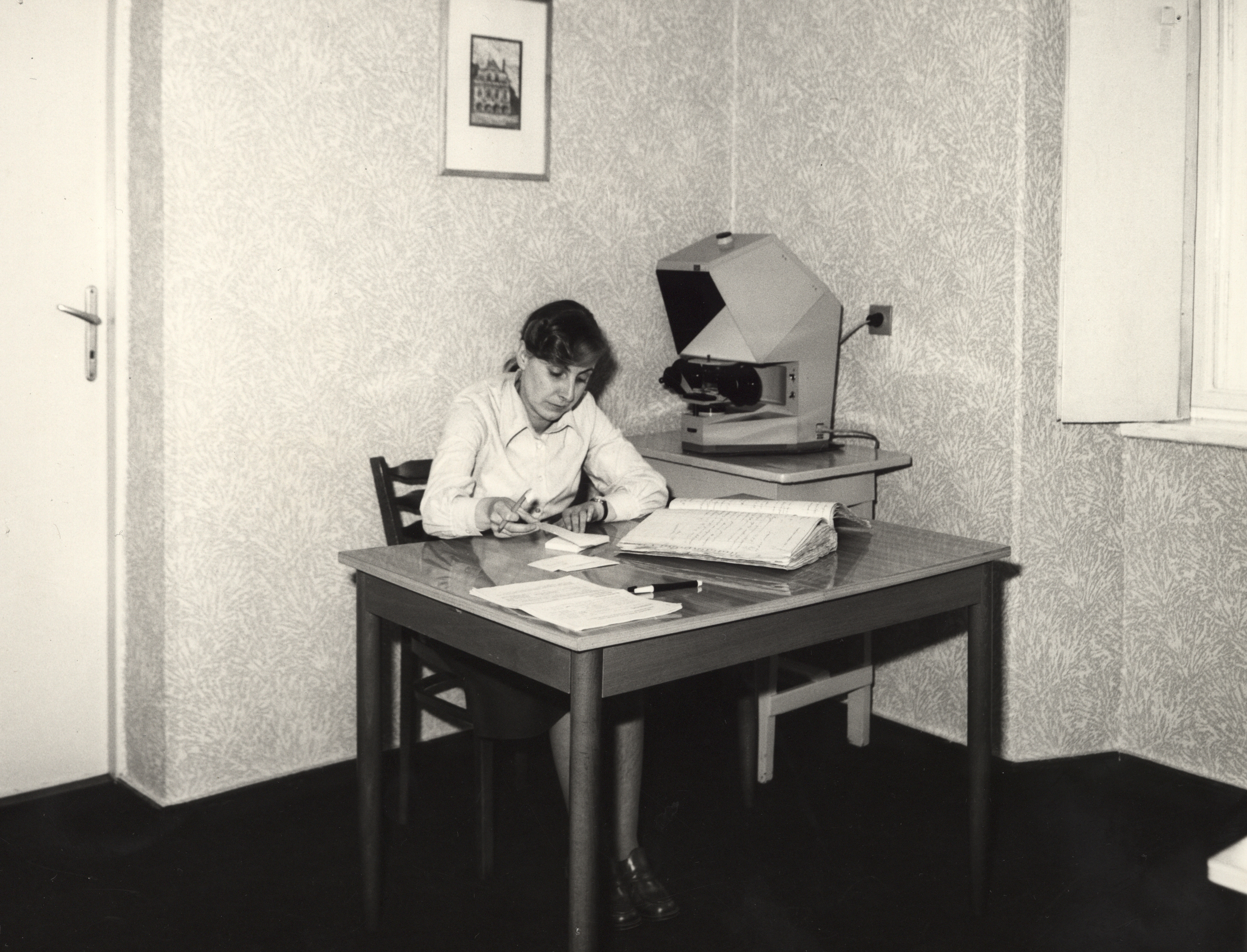Kobieta siedzi za stołem i przegląda dokumenty.