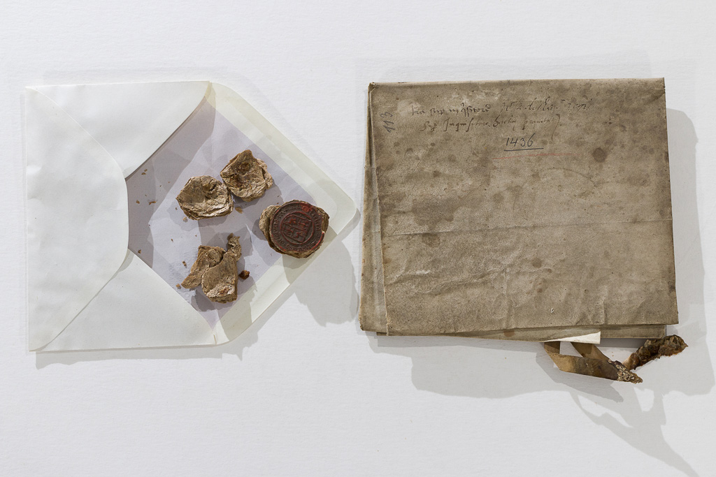 Stary dokument złożony w kostkę, obok w kopercie połamana pieczęć.