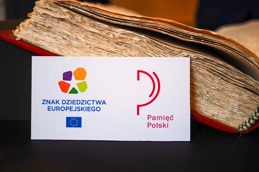 Bok księgi z logotypami Znaku Dziedzictwa Europejskiego i Polskiej Listy Krajowej Programu UNESCO Pamięć Świata.