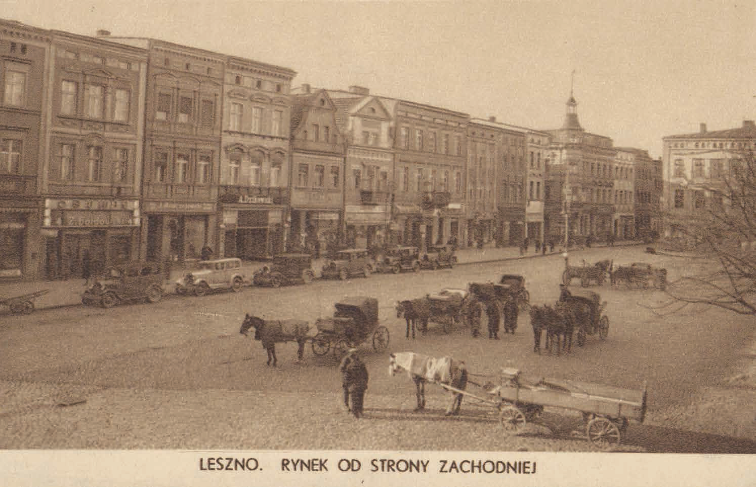Widok Rynku w Lesznie. Widoczne kamieniczki, auta i powozy. 