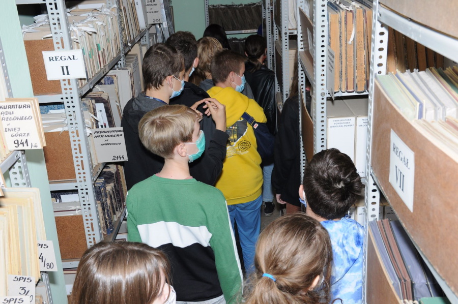 Uczniowie między regałami z archiwaliami