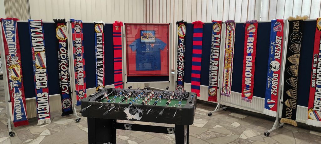 Prezentacja szalików klubu, w środku stolik z piłkarzami.