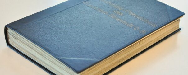 Zdjęcie księgi po konserwacji, widać odnowioną oprawę z kolorze ciemnoniebieskim z wyraźnym tłoczonym napisem, karki zszyte i uporządkowane.