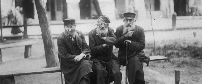 Trzech Żydów siedzi na ławce w parku.