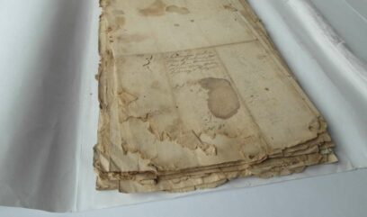 Plik dokumentów z licznymi przebarwieniami papieru i ubytkami