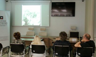 Grupa osób ogląda wyświetlany na ekranie czarno-biały film.