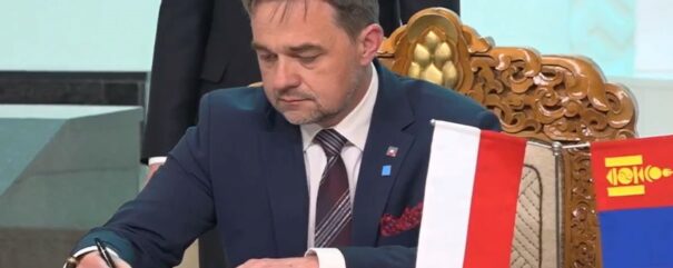 Dyrektor Pietrzyk siedzi przy stoliku i podpisuje memorandum.