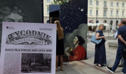 Tygodnik Ilustrowany – wydanie specjalne poświęcone Kopernikowi. W tle na placu stoją bryły wystawy. Obok wystawy przechadzają się ludzie.