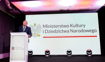 Minister Gliński za mównicą. W tle ekran z logotypem Ministerstwa Kultury i Dziedzictwa Narodowego.