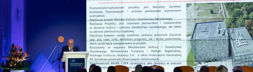 Dyrektor Ryszard Wojtkowski stoi za mównicą. W tle na ekranie prezentacja.