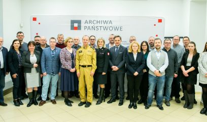 Zdjęcie grupowe na ściance z logo Archiwa Państwowe.