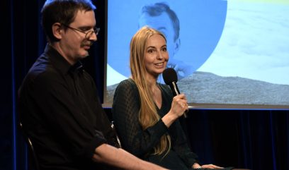 4 osoby siedzą na scenie. W tle na ekranie grafika promująca publikację. Do mikrofonu mówi Olga Nasińska.