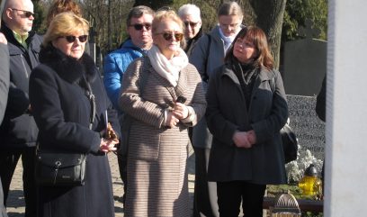Grupa uczestników upamiętnienie stoi obok grobu.