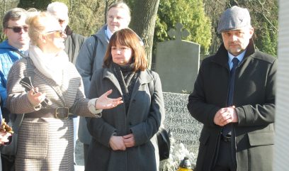 Grupa uczestników upamiętnienie stoi obok grobu.