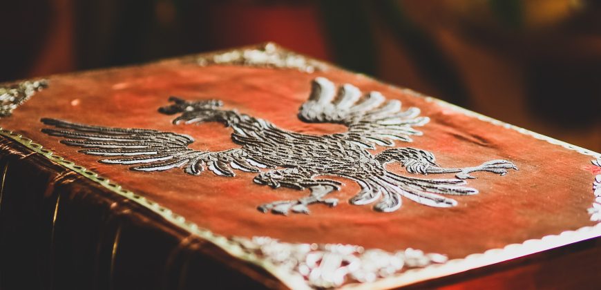 Pudło w ozdobnej oprawie. Oprawa przedstawia herb Królestwa Polskiego wyszyty srebrną nicią na czerwonym aksamicie.