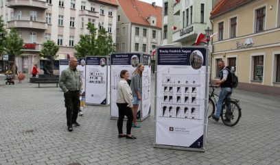 Grupka osób ogląda stojące na placu plansze wystawy.