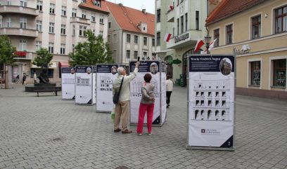 Grupka osób ogląda stojące na placu plansze wystawy.