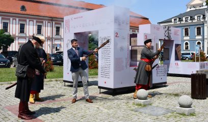 Dwie osoby oddają symboliczny wystrzał ze starodawnej broni.