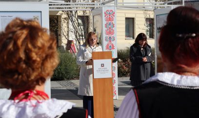 Dyrektor Rutkowska stoi za mównicą. Za nią stoi wystawa.