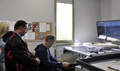 Sala digitalizacji. Pracownik pokazuje gościom proces digitalizacji.