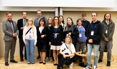 Aula wykładowa. Zdjęcie grupowe 14 osób na scenie.