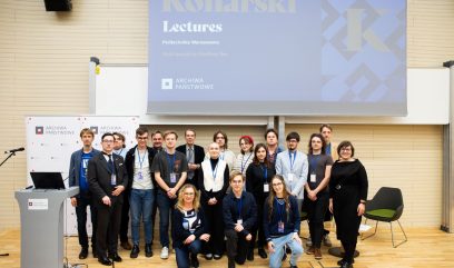 Aula wykładowa. Zdjęcie grupowe 19 osób na scenie. Nad nimi ekran z planszą promocyjną wydarzenia.