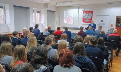 Publiczność siedzi na sali, na środku przemawia archiwista.