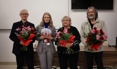 4 osoby pozują do zdjęcia. 3 darczyńców trzyma bukiety kwiatów, dyrektorka Archiwum trzyma w ręku maskotkę Archiwka w czapce Mikołaja.