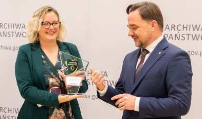 Natalia Marozas trzyma szklaną statuetkę, obok stoi dyrektor Pietrzyk.