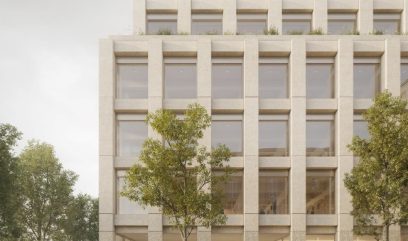 A modern, rectangular building with large, evenly spaced windows and a light stone facade. It has four floors, a minimalist design, and a touch of greenery on the roof. Trees and people are prominent in the foreground, creating an urban and inviting atmosphere.