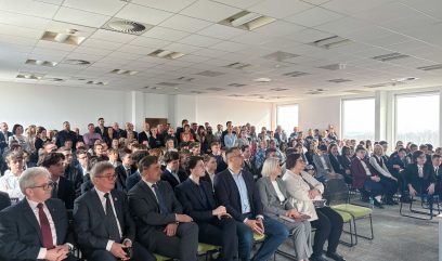 Sala konferencyjna. Publiczność siedzi na sali.