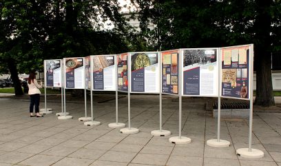 Plansze wystawy stoją na skwerze. 1 osoba ogląda wystawę.