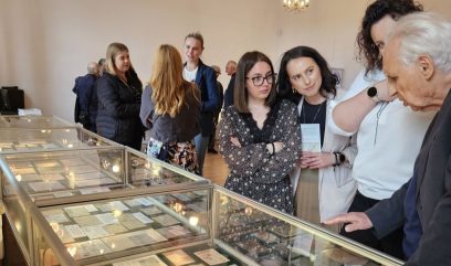 Sala wystawowa. 11 osób ogląda wyłożone w szklanych gablotach i na stolikach materiały archiwalne.