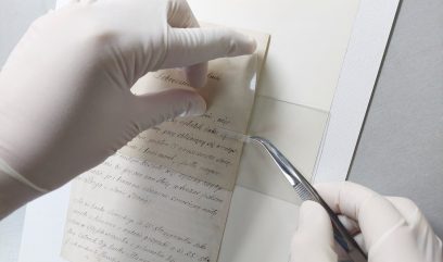 Konserwatorka w białych rękawiczkach przykłada biały pasek do papieru.