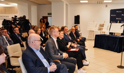 Publiczność siedzi na sali konferencyjnej.
