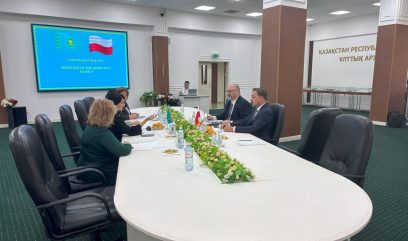 Sala konferencyjna. 5 osób siedzi przy stole i rozmawia.