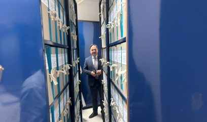 Magazyn archiwalny. Dyrektor Pietrzyk stoi między regałami.