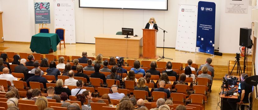 Aula wykładowa. Anne J. Gilliland przemawia do mikrofonu. Przed nią siedzi publiczność.