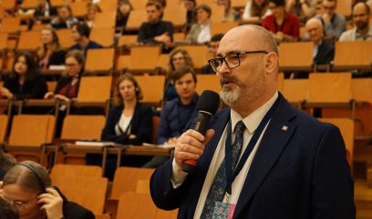 Publiczność siedzi na auli. Mężczyzna z publiczności zadaje pytanie.