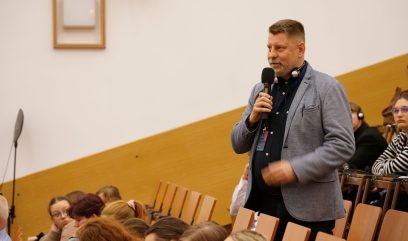 Publiczność siedzi na auli. Mężczyzna z publiczności zadaje pytanie.
