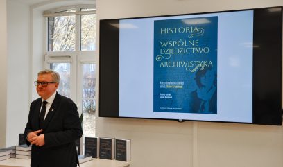 Jacek Krochmal stoi przed stolikiem z książkami.