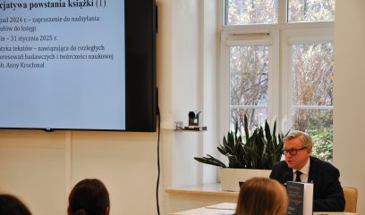 Jacek Krochmal siedzi za stolikiem. Przed nim stoi otwarty laptop.