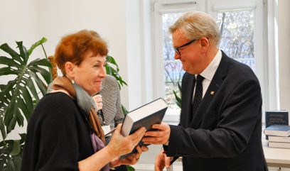 Jacek Krochmal wręcza egzemplarz publikacji kobiecie.