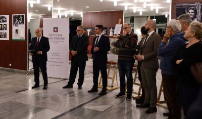 Hol budynku. 9 osób stoi w półkolu. Dyrektor Wojtkowski przemawia.