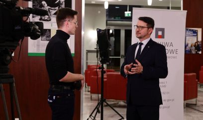 Hol budynku. Dyrektor Górecki udziela wywiadu dziennikarzowi.