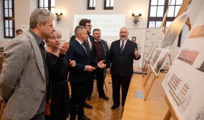Kilka osób ogląda plansze wystawiona na stelażach.