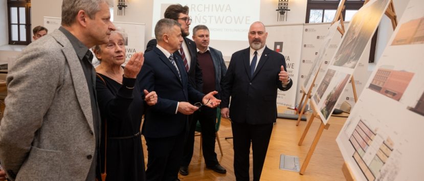 Kilka osób ogląda plansze wystawiona na stelażach.