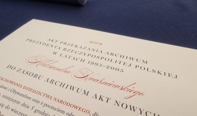 Zbliżenie oficjalnego polskiego dokumentu zatytułowanego Akt przekazania archiwum Prezydenta Rzeczypospolitej Polskiej w latach 1995-2005 na niebieskiej powierzchni, z formalną czcionką i nazwiskiem Aleksandra Kwaśniewskiego zapisanym dużym, ozdobnym pismem.