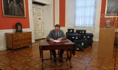 Dyrektor Pietrzyk siedzi przy stoliku i podpisuje dokumenty.